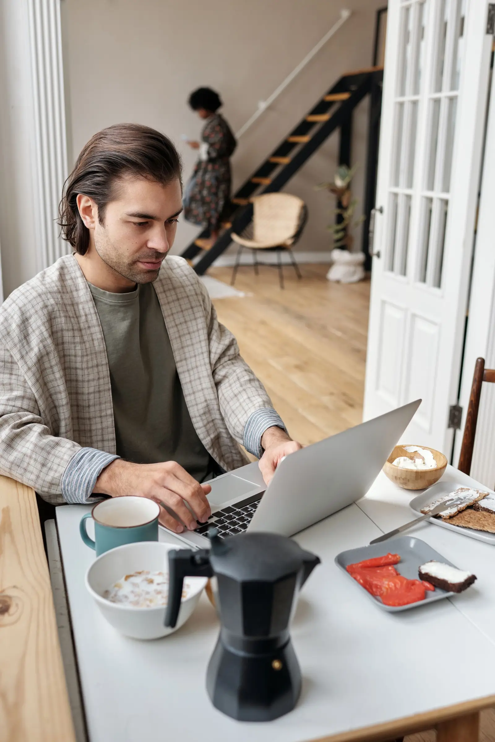 Man werkt aan de ontbijttafel op zijn laptop, met een kop koffie erbij